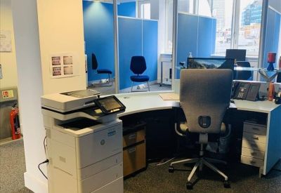 Bright workspace featuring a modern workstation and a large multifunctional printer.
