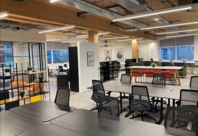 Spacious open-plan workspace with industrial ceilings and modern black desks.