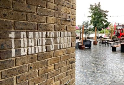 Outdoor patio area with wooden seating and brick signage for Dane's Yard.