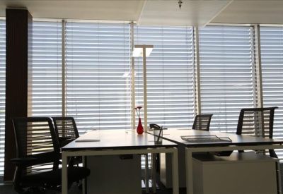 Bright private office with two desks, ergonomic chairs, and natural light from window blinds.