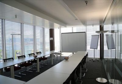 Large conference room with long white tables, projection screen, and floor-to-ceiling windows.
