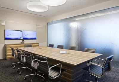 Modern conference room featuring a large wood-topped table and frosted glass wall partitions.