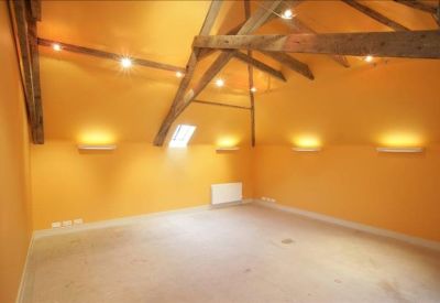Spacious attic office with exposed timber beams and warm yellow walls.