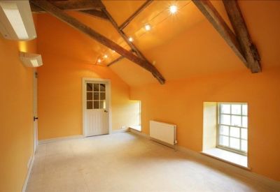 Bright workspace featuring vaulted ceilings, wooden trusses, and natural light from a skylight.