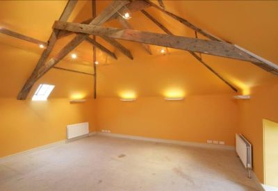 Large open-plan room with warm lighting and rustic wooden roof structure.