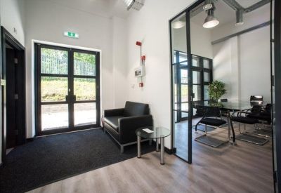 Modern reception area featuring a black leather sofa and glass partition walls.