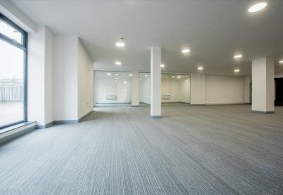 Spacious open-plan office with grey carpeting and bright recessed lighting.