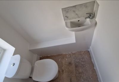 Modern compact restroom with white fixtures and wood-effect flooring.
