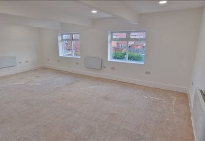 Bright corner office space with recessed lighting and multiple wall-mounted radiators.