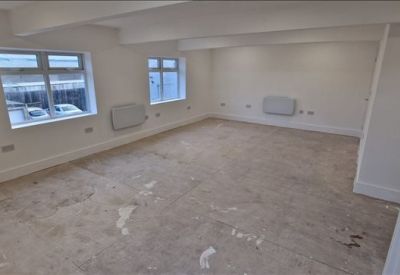 Wide-angle view of a refurbished office floor featuring white walls and staircase railing.