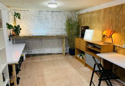 Breakout area with light wood flooring, a workbench, and a mix of white and wood-paneled walls.