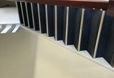 Compact kitchenette area viewed through a narrow opening, showing white cabinets and tiled walls.