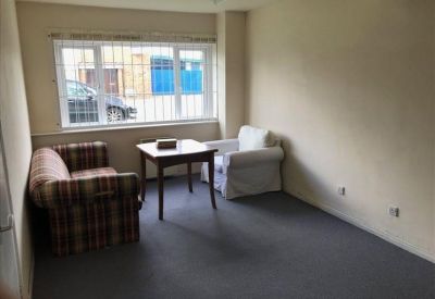 Private office space with plaid sofa, white armchair, and wooden table near a large window.