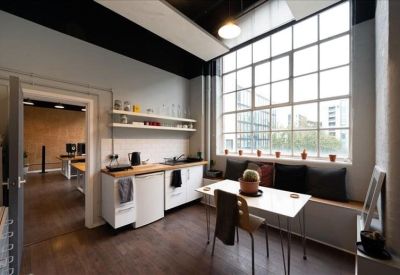 Bright communal kitchen and dining area with a window-side bench and modern table.