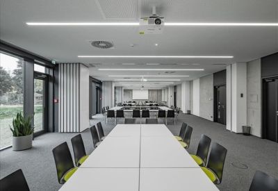 Long white boardroom table with green chairs and a ceiling-mounted projector.