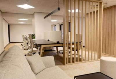 Modern coworking space featuring a wooden slat room divider and comfortable grey sofa.
