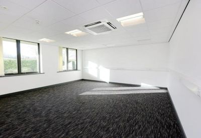 Bright, empty office suite with dark grey carpeting and large windows.