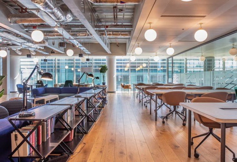 Large open-plan coworking space with timber flooring and industrial ceilings.