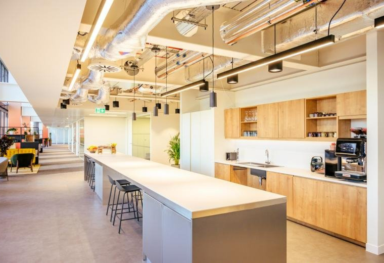 Spacious communal kitchen and dining area at 22 Bishopsgate, London with wood cabinetry and long island.