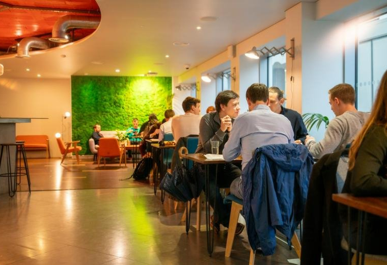Spacious communal lounge at 69 Wilson Street, London, England featuring a green moss wall and cafe seating.