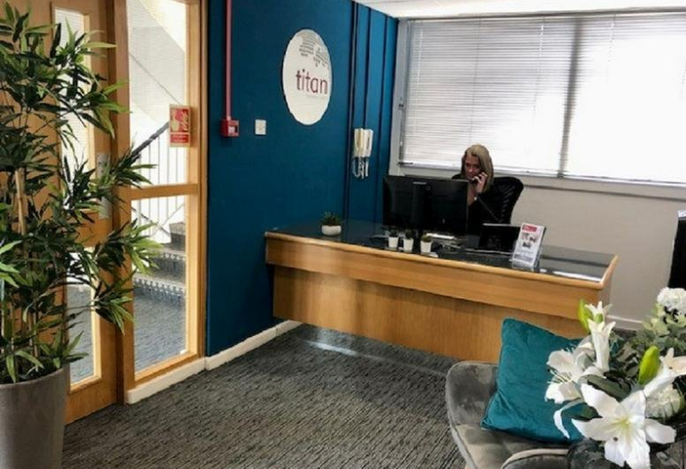Reception area at Euroway House with a branded teal feature wall and wooden front desk.