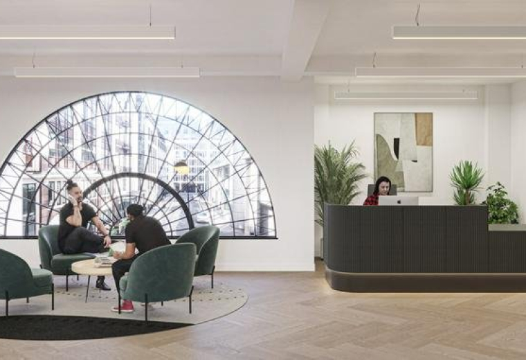 Bright reception area with a curved dark desk, velvet lounge chairs, and a large semi-circular window.
