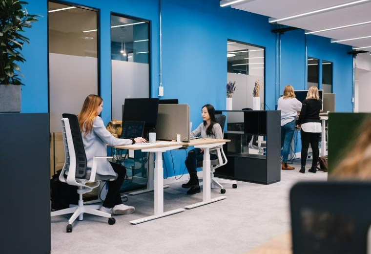 Spacious open-plan workspace at 10, Havellandstraße with blue feature walls and height-adjustable desks.