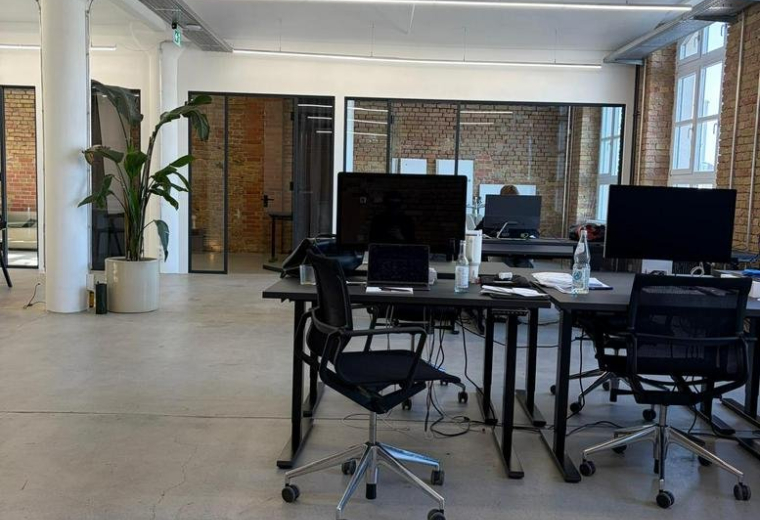 Spacious open-plan workspace at 145, Köpenicker Straße featuring modern desks and potted plants.