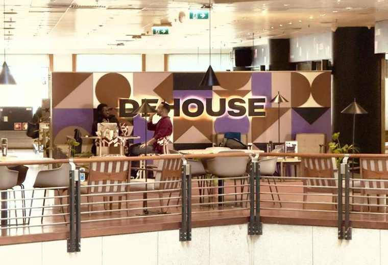 Mezzanine lounge area at Edificio Península Business Center with geometric murals and wooden accents.