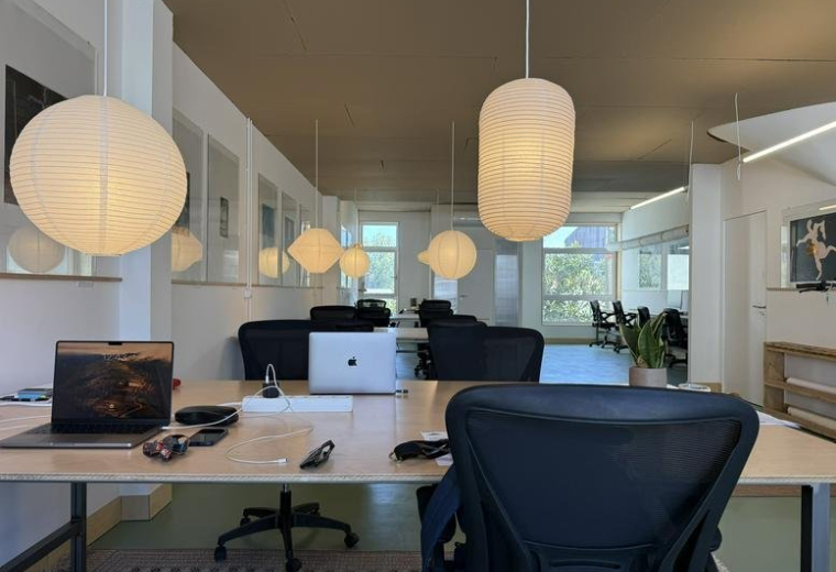 Spacious open-plan workspace at Rua do Almirante Leote do Rego, 204 with warm globe lighting and modern desks.