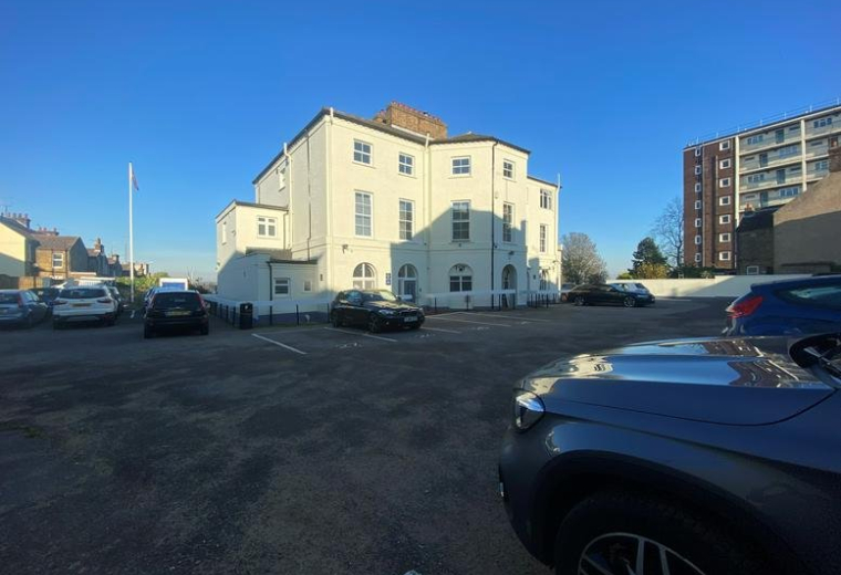 Exterior view of the white period building at 47 The Terrace showing the car park and facade.