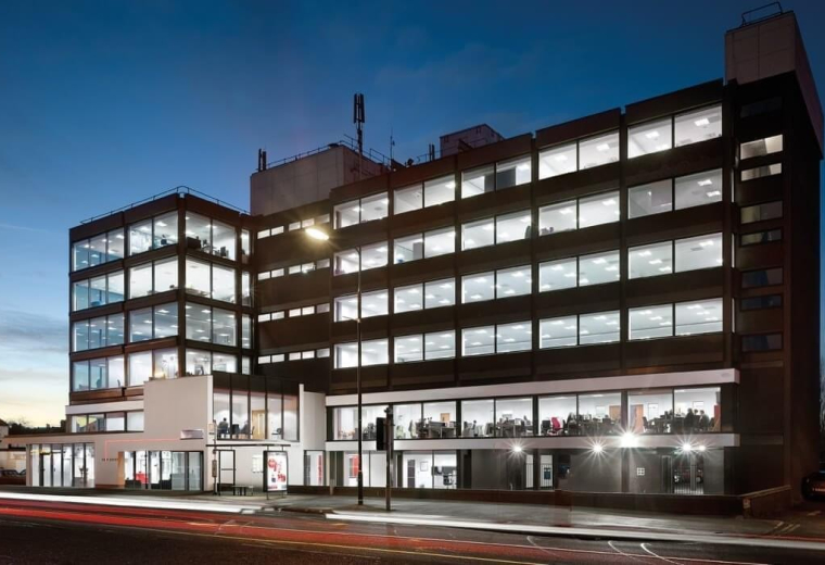 Wide exterior view of the multi-story office building illuminated at dusk.