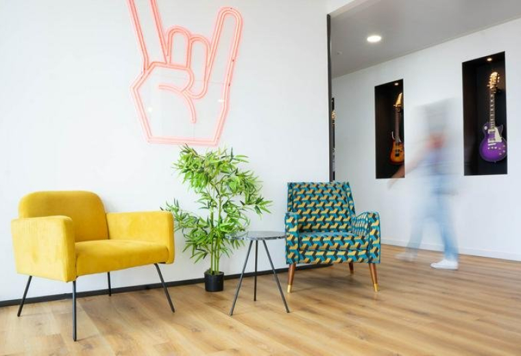 Colorful lobby at 4 chemin de l’arenas with rock sign wall art and modern armchairs.
