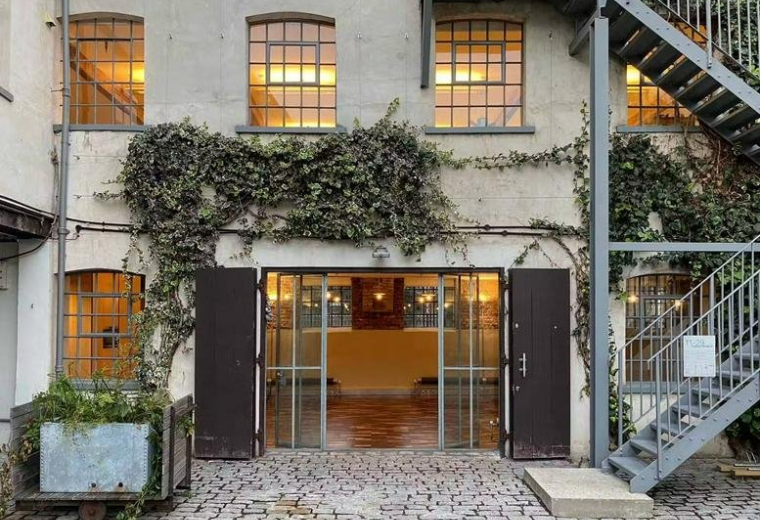 Exterior of the industrial brick building at 11, Fashion Street with climbing ivy and an external steel staircase.