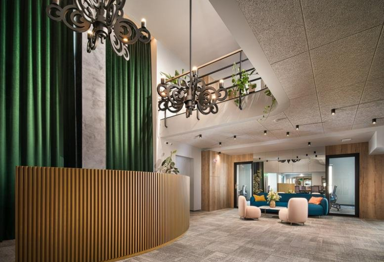 Spacious lobby with a fluted wooden desk, green curtains, and ornate black chandeliers.