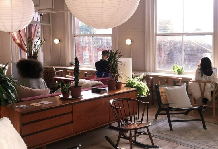 Sunlit lounge area featuring mid-century modern furniture, paper lanterns, and indoor plants.