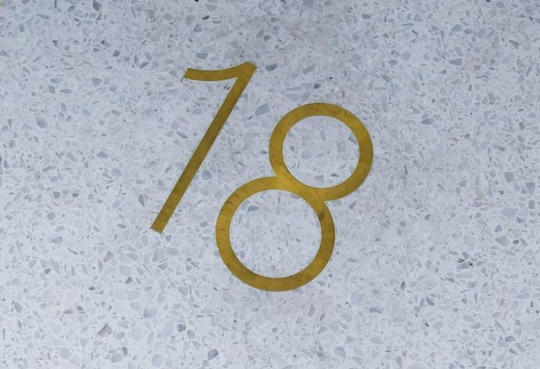 Close-up of the number 18 inlaid in brass on a light terrazzo floor.