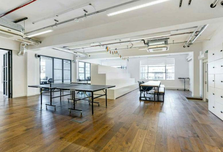 Spacious communal area with wooden floors, a ping pong table, and bench seating.