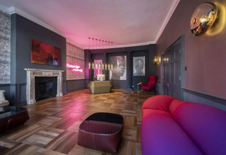 Reception lounge with a purple sofa, neon sign, and parquet flooring.