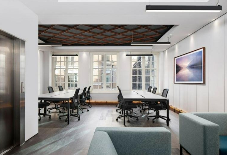 Bright open-plan office with white workstations and framed artwork on the wall.