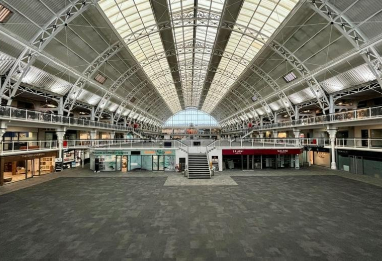Grand communal hall under a massive barrel-vaulted glass roof with multi-level internal balconies.