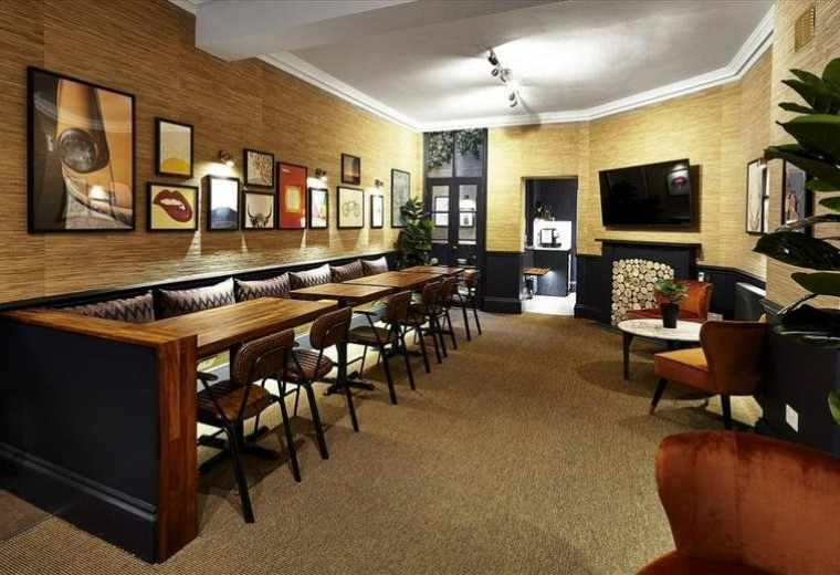 Spacious communal lounge at 54 Poland Street with wood paneling, gallery wall, and banquette seating.