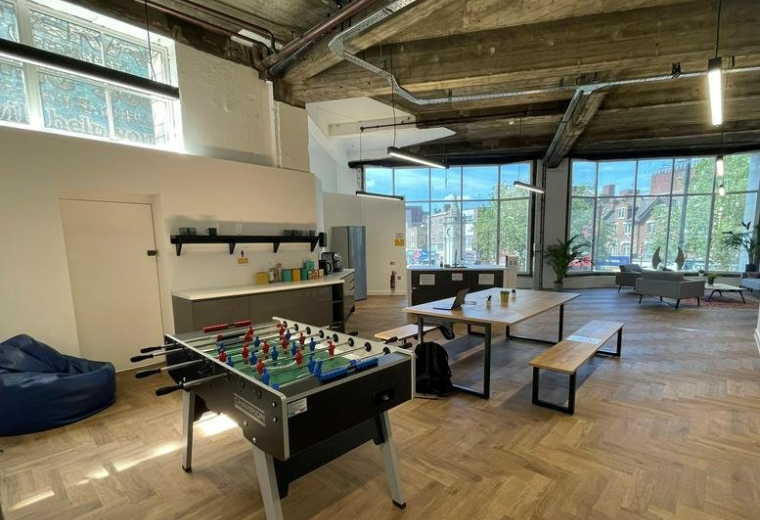 Spacious communal breakout area at 71 Lewisham High Street with foosball table and high ceilings.
