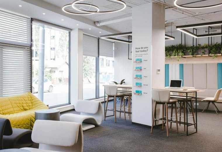 Spacious sunlit common area at Twins Centre with modern white seating, high tables, and ring pendant lights.