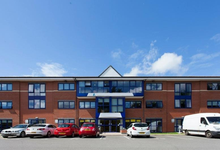Exterior view of the brick facade and parking area at Atlas House, Caxton Close, Wigan.