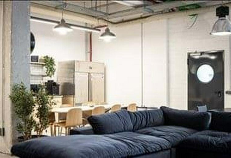 Spacious communal lounge at Charlottenburger Straße 62 with a large blue sectional sofa and dining area.
