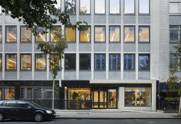 Exterior facade and entrance of 22 Berners Street with large windows and a black car parked in front.