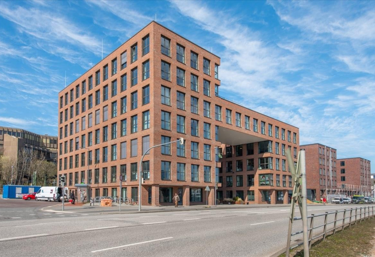 Modern multi-story brick exterior of the Kaistrasse 90 building with a unique open archway.