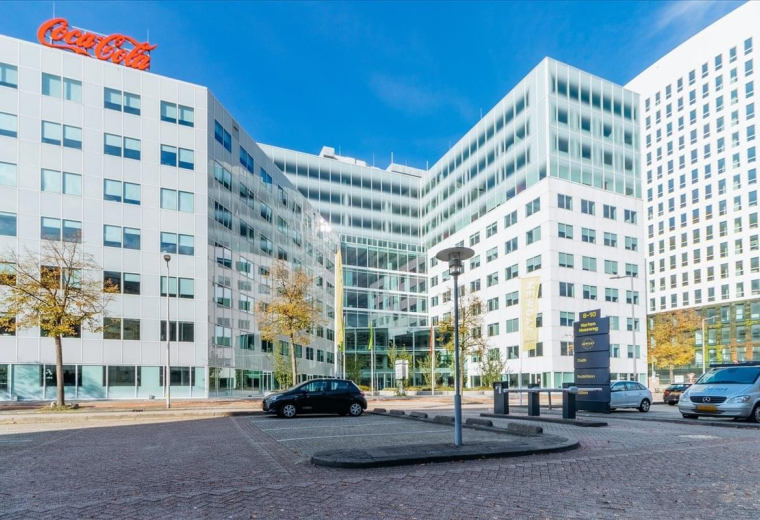 Exterior view of the modern white office building at Marten Meesweg 25-G with a clear blue sky.