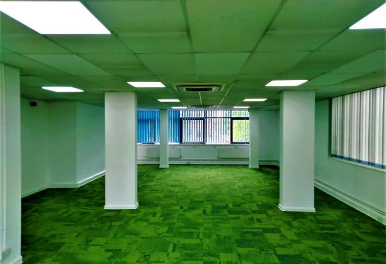 Spacious open-plan office space at Ramsden House with green carpet and large windows.